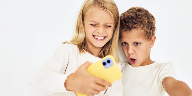 Zwei Kinder machen ein Selfie mit gelbem Handy,  beide in weißen T-Shirts