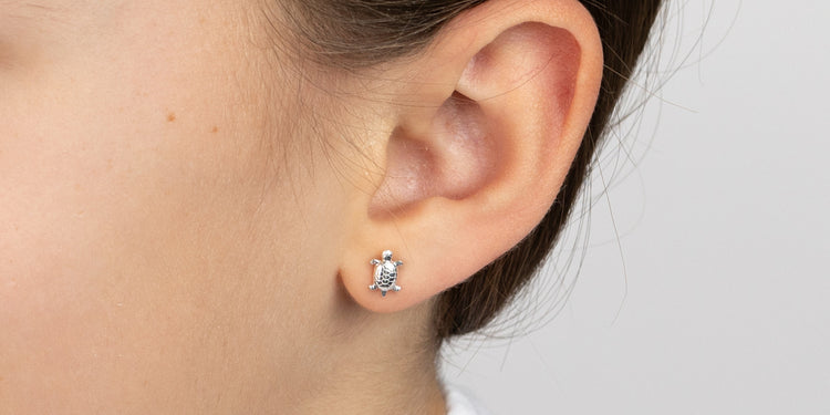 Silberner Ohrstecker mit Schildkröten-Motiv am Ohr getragen